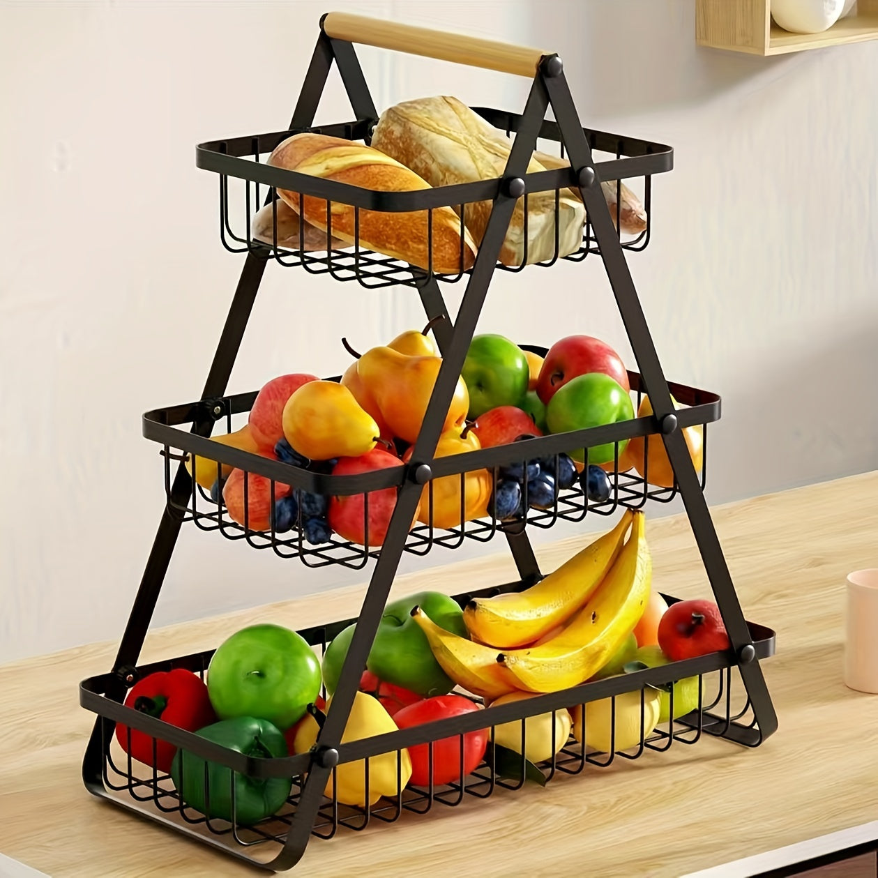 A contemporary metal fruit and vegetable basket featuring a detachable bowl-shaped storage compartment and a wooden handle for kitchen organization. Ideal for gifting during Christmas or Halloween, this handy organizer can be used on the countertop or in