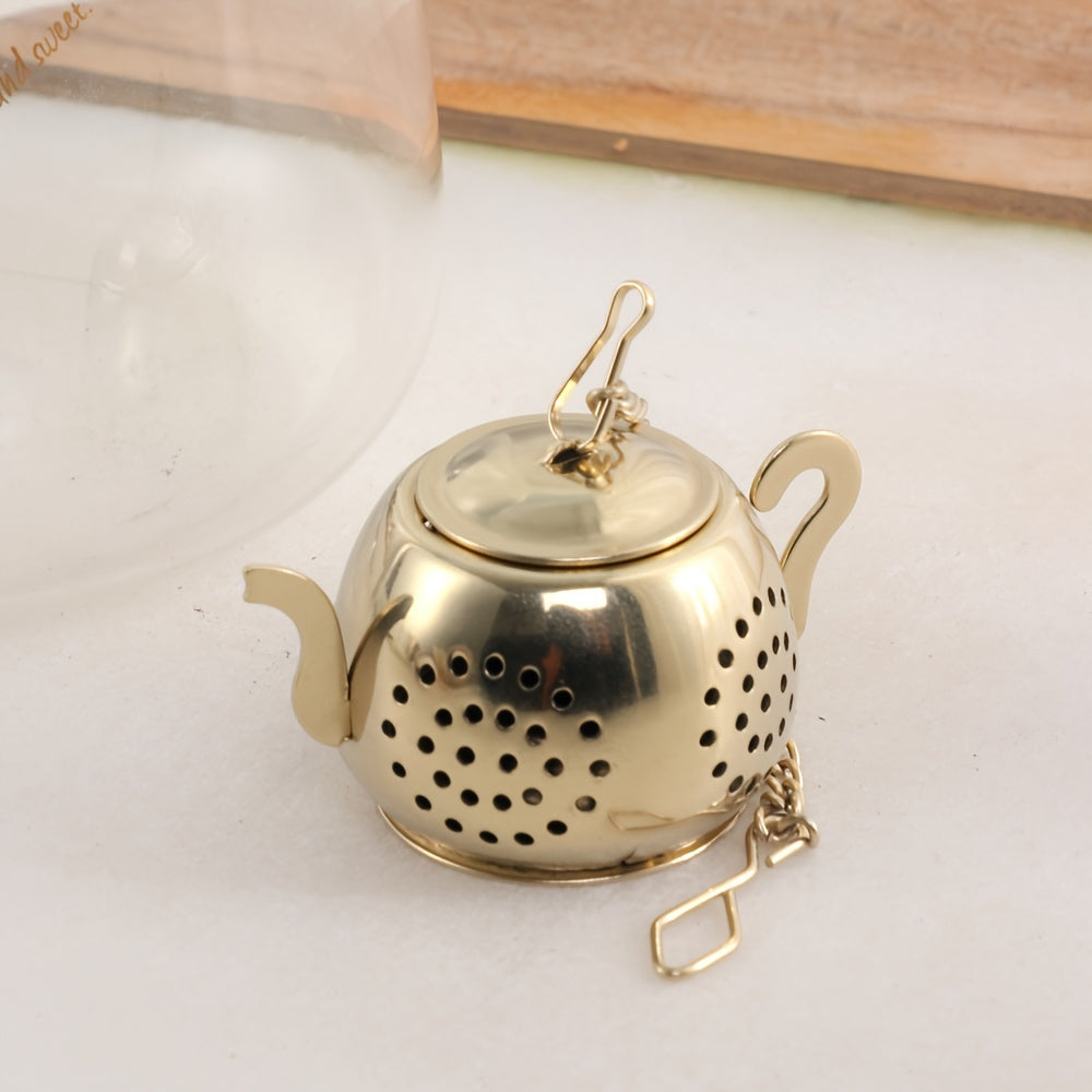 Golden rose stainless steel teapot-shaped tea strainer with uniform filter holes and hanging chain for cups.