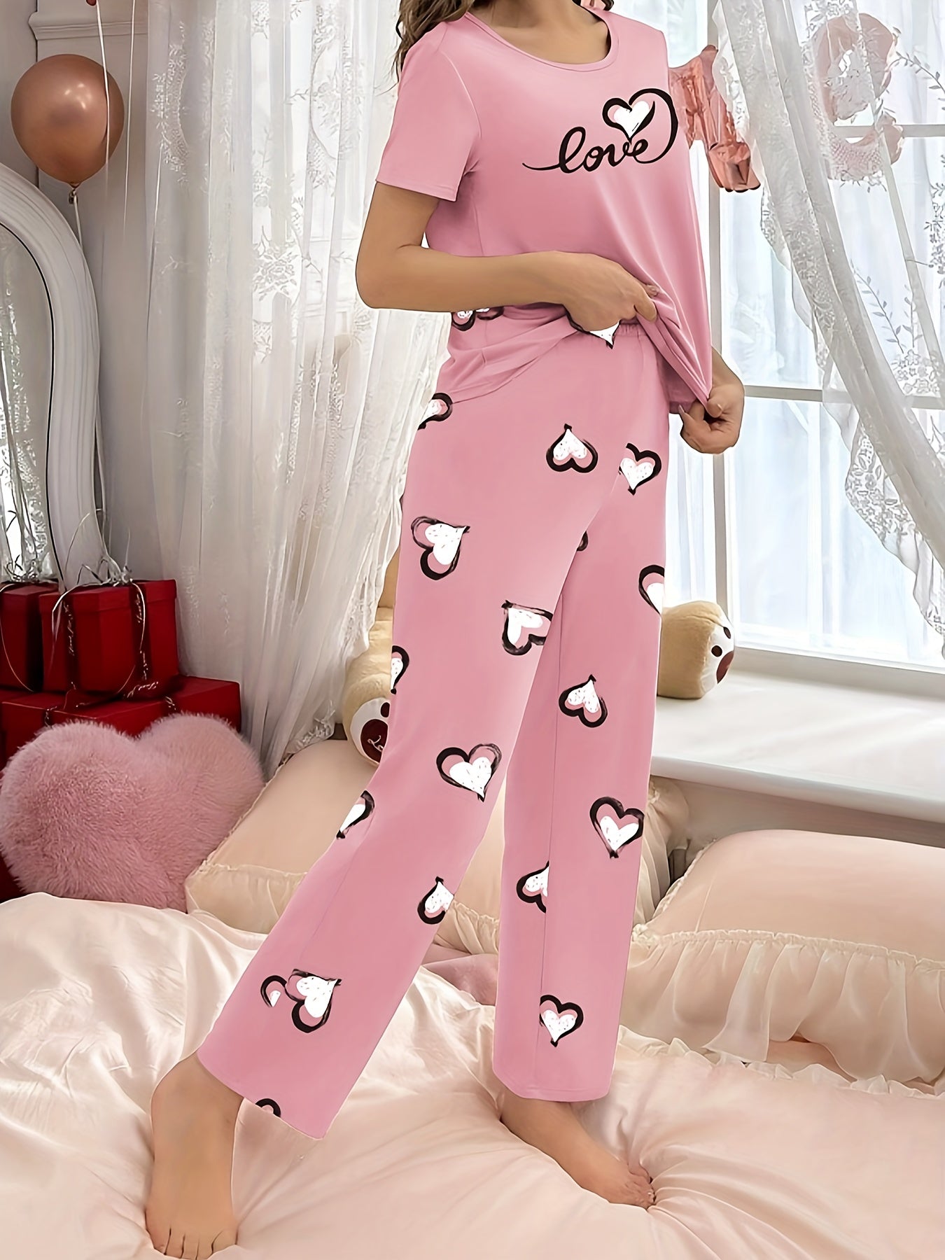 Stylish pink heart print pajama set for women with comfy short sleeve top and long pants, made of breathable polyester blend fabric.