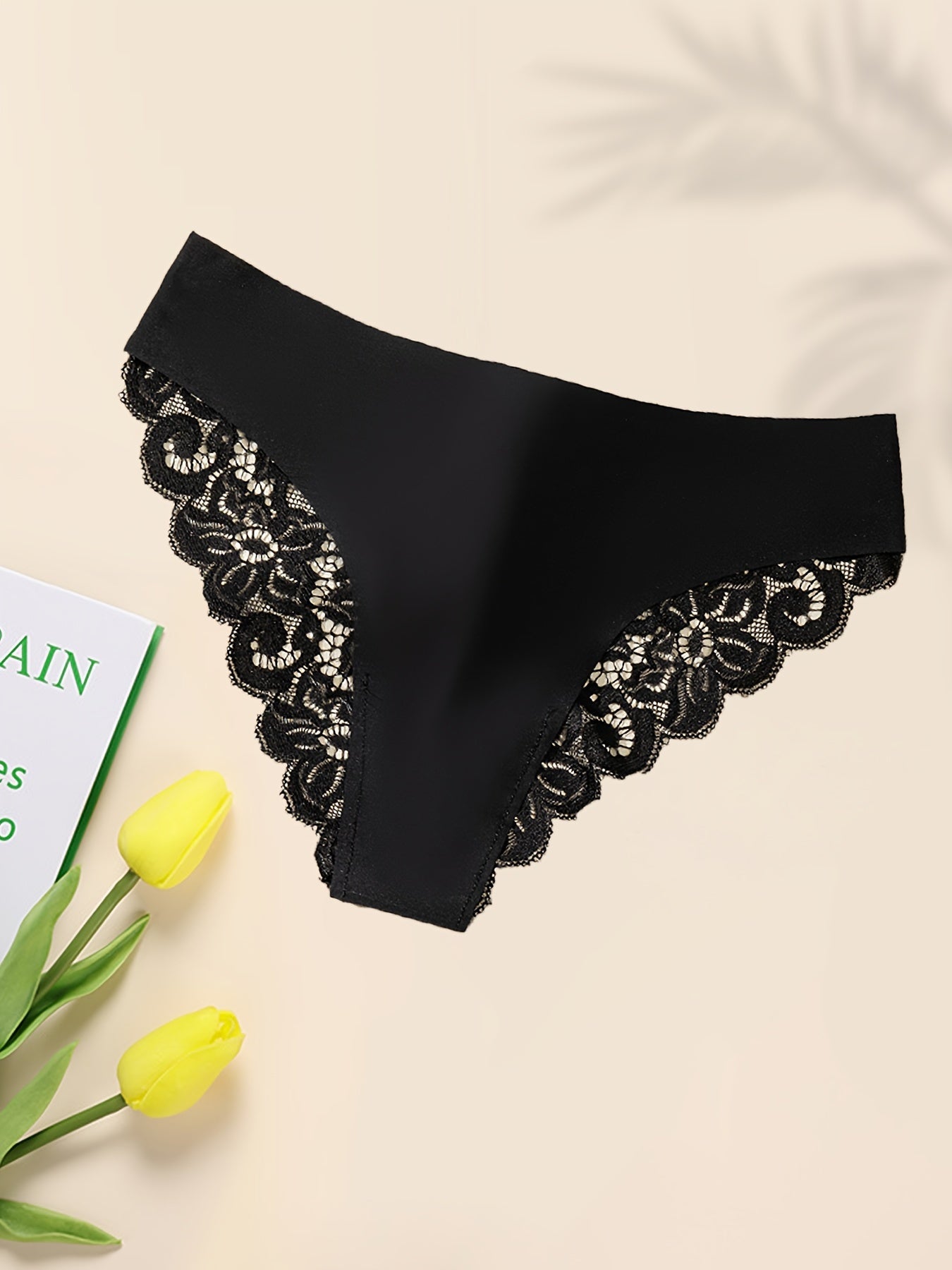 Women's black lace panties with low-rise, seamless design. Made from soft nylon/elastane blend with scalloped trim and cut-out detail. Hand washable. Elegant solid color underwear for