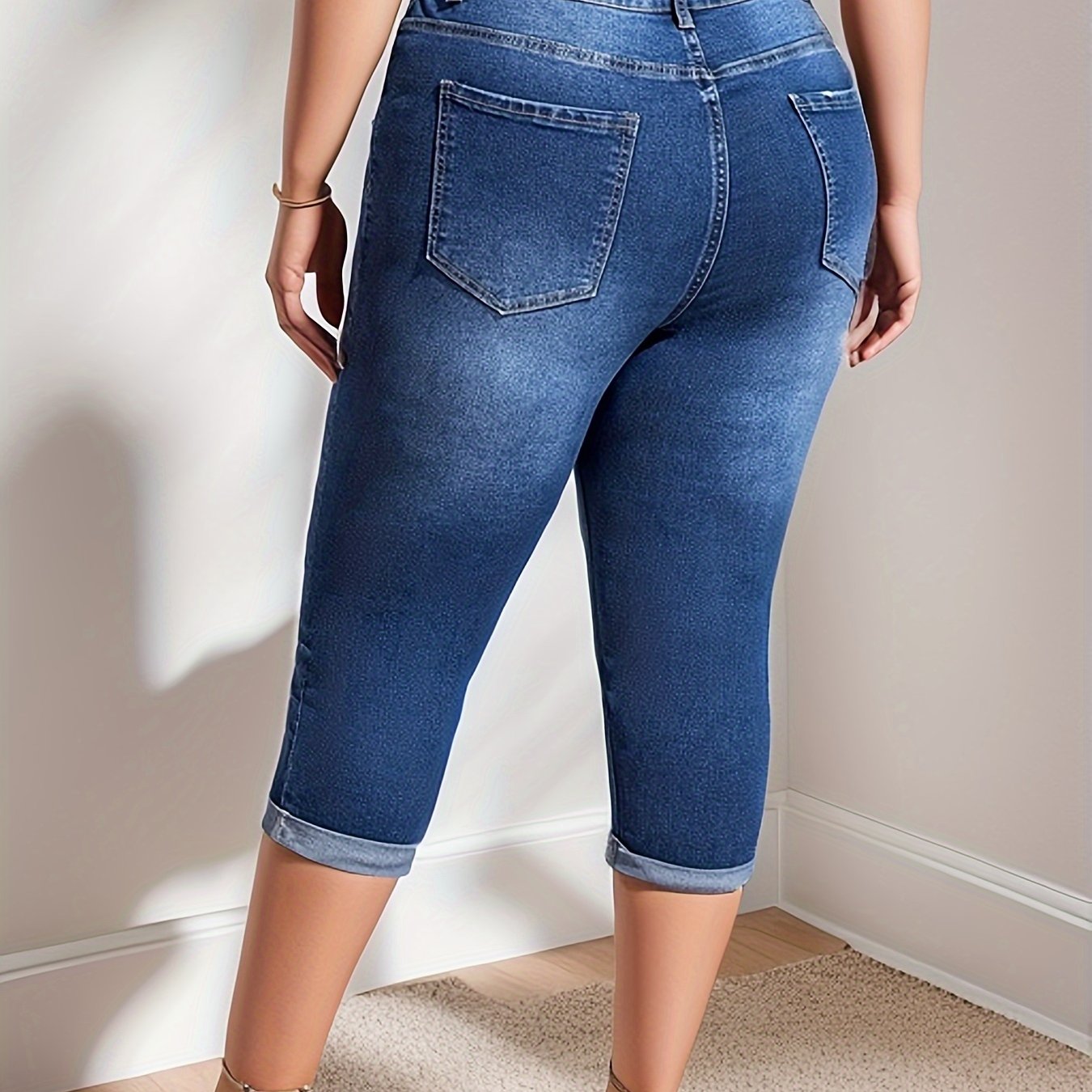 Plus size women's high stretch capri denim pants in washed blue with whiskering and roll-up hem.