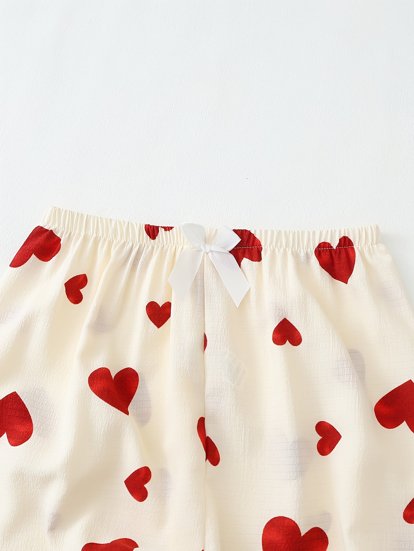 Red heart print pajama set for women with long sleeves, lapel collar, and comfortable fabric made of 95% polyester and 5% elastane. Suitable for all seasons.