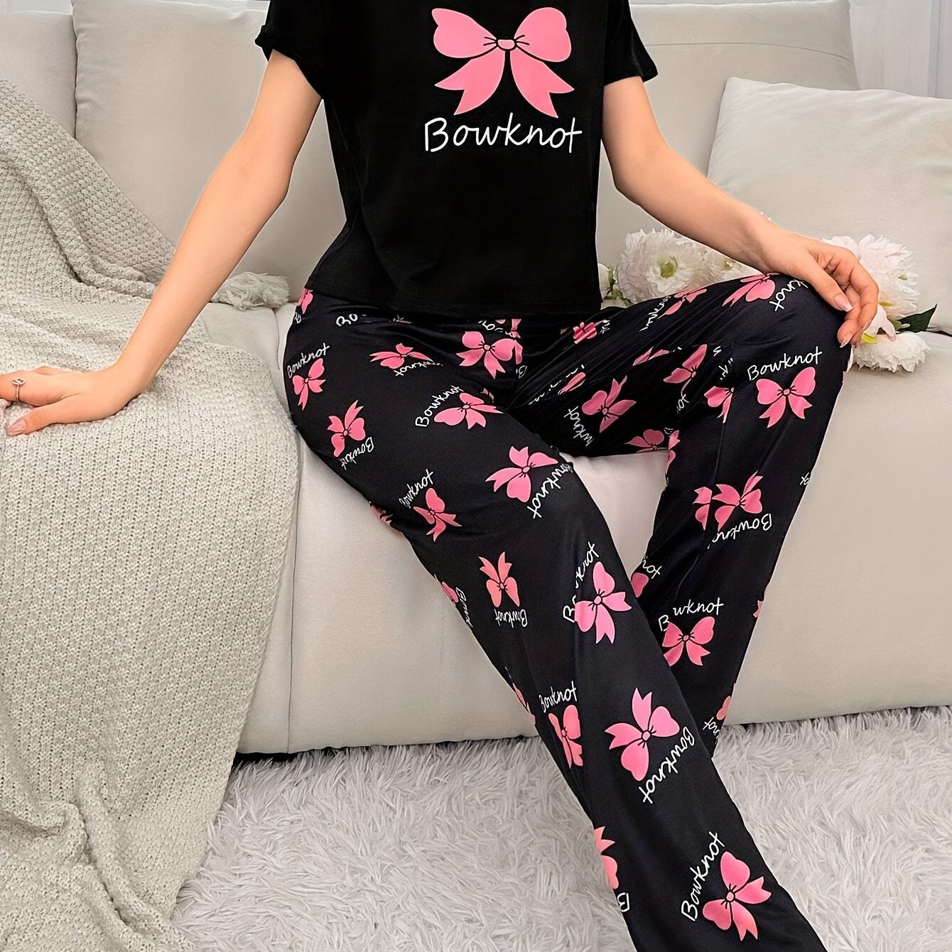 Cozy bowknot pajama set for women with short sleeves and elastic waistband pants. Made from soft, machine washable polyester blend in black with pink butterfly print.