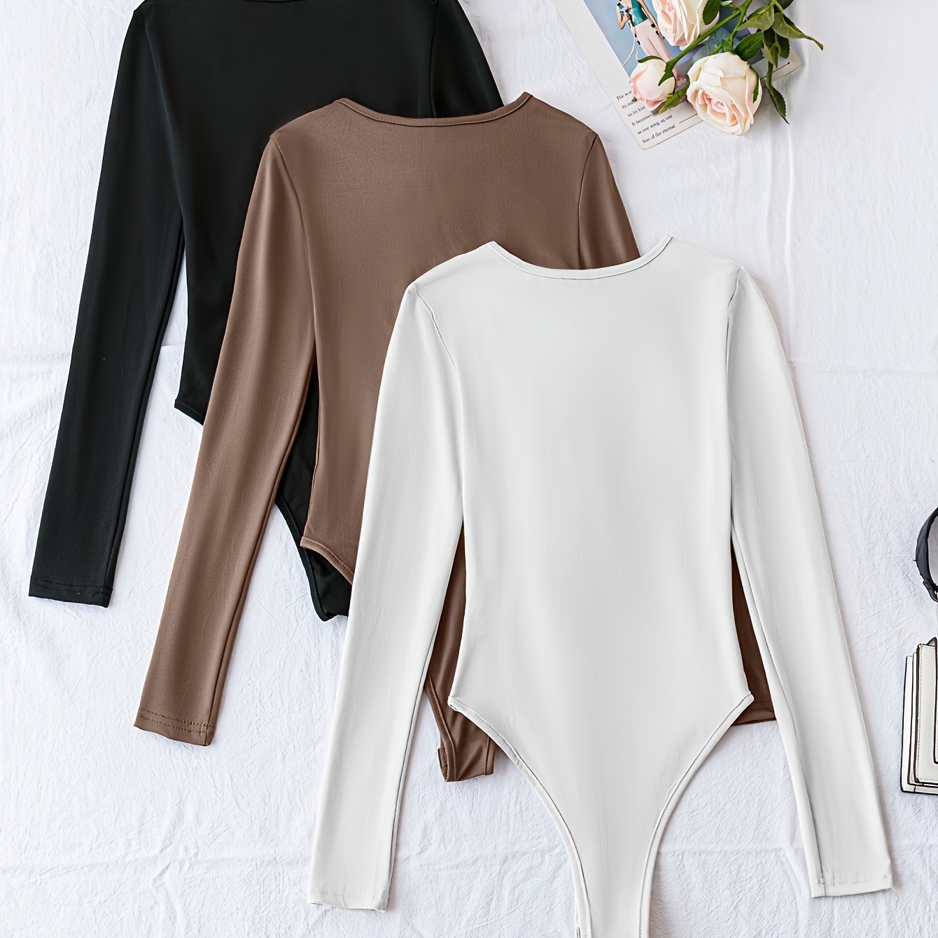 Pack of three solid crew neck long sleeve bodysuits for women. Casual one-piece clothing.