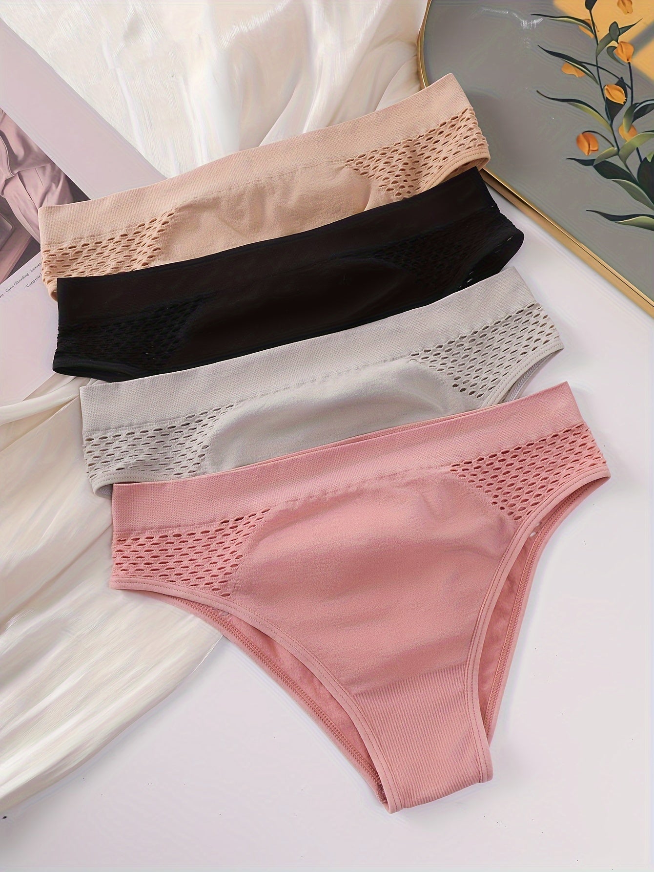 Four-pack of low-rise briefs for women, with hollow-out design and medium support. Made from a blend of 90% Polyamide and 10% Elastane knit fabric, in a solid color. Lightweight at 200gsm