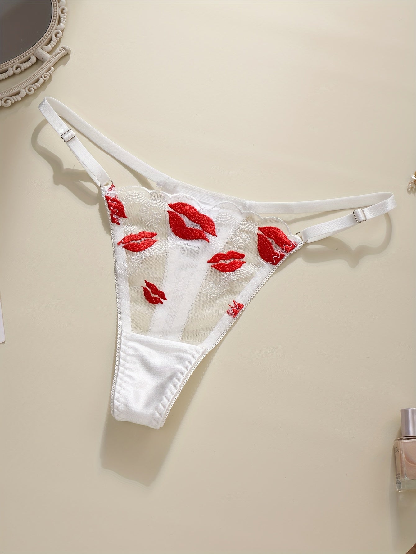 Floral embroidered lingerie set with sexy lips pattern, made of polyester knit fabric. Includes a geometric-patterned bralette and thong, no padding.