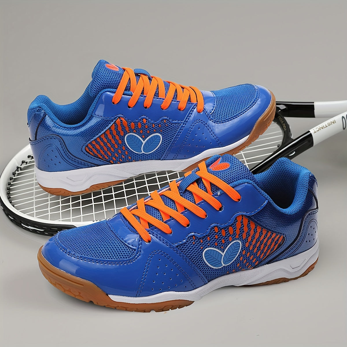 Breathable badminton and table tennis shoes in blue with orange accents, featuring a durable sole and lace-up design for all-season athletic wear.