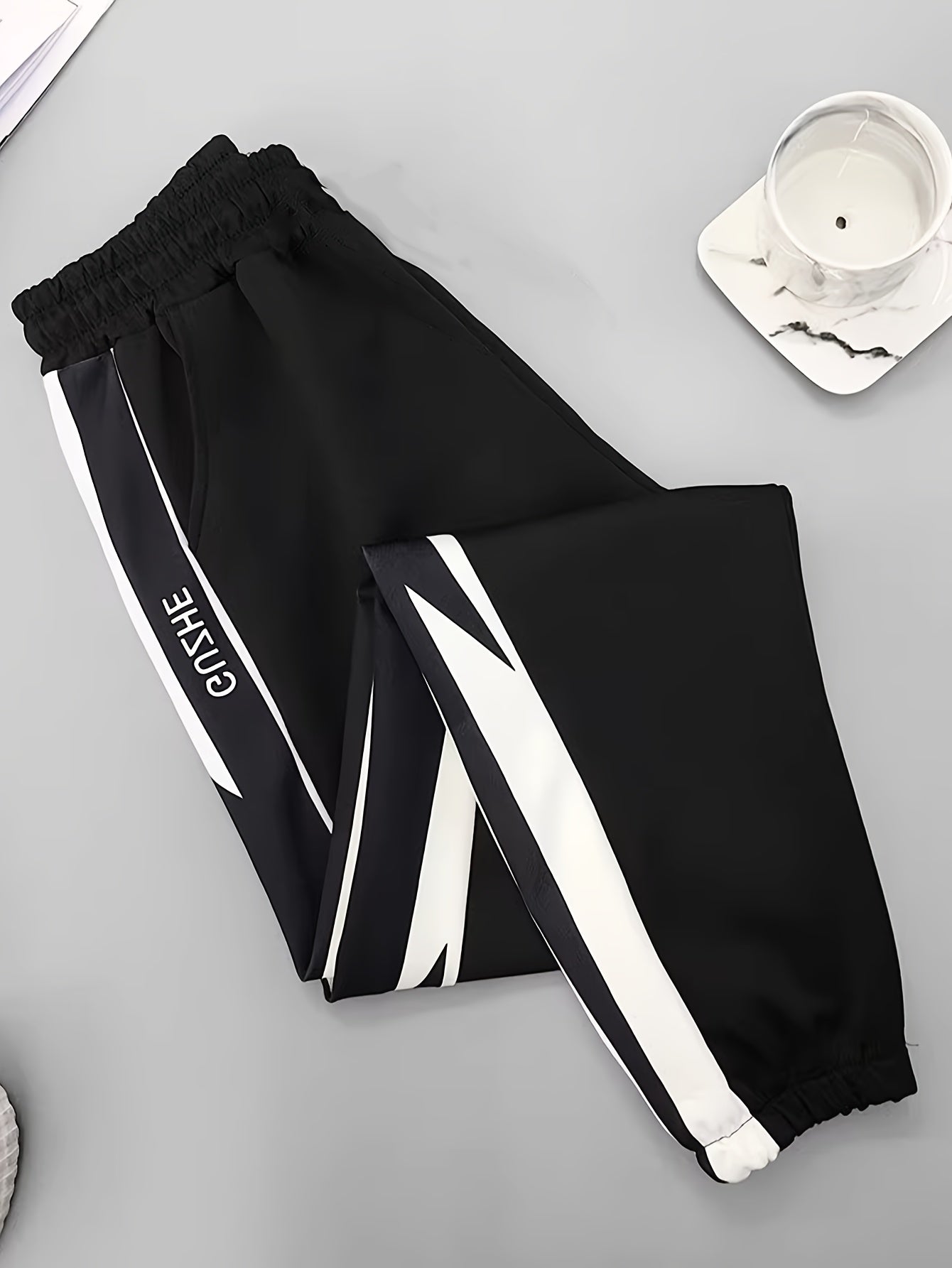 Men's lightweight stretch joggers with contrasting side panels and elastic waistband, perfect for spring/fall sports and leisure activities. Made from a polyester and elastane blend.