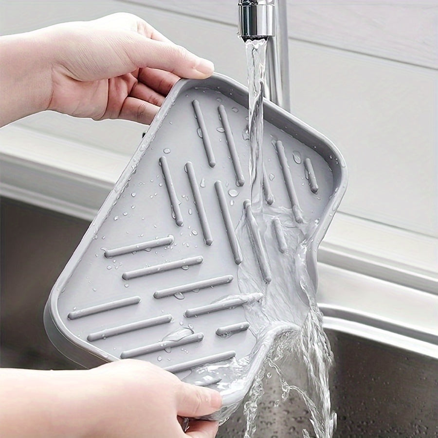 Silicone sink mat with soap dispenser, sponge drain, and countertop storage tray for drying and organizing bathroom accessories.