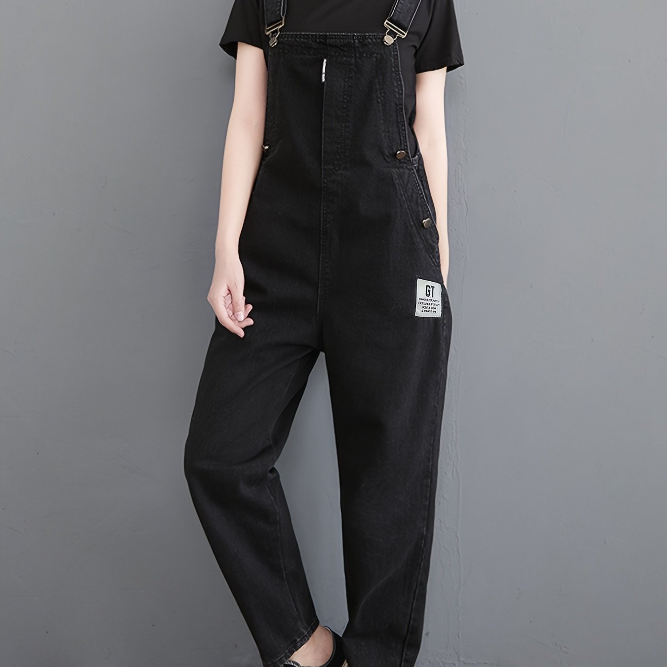 Classic black denim overalls for women with adjustable straps, loose fit, slant pockets and harem hem in non-stretch fabric for all-season wear.