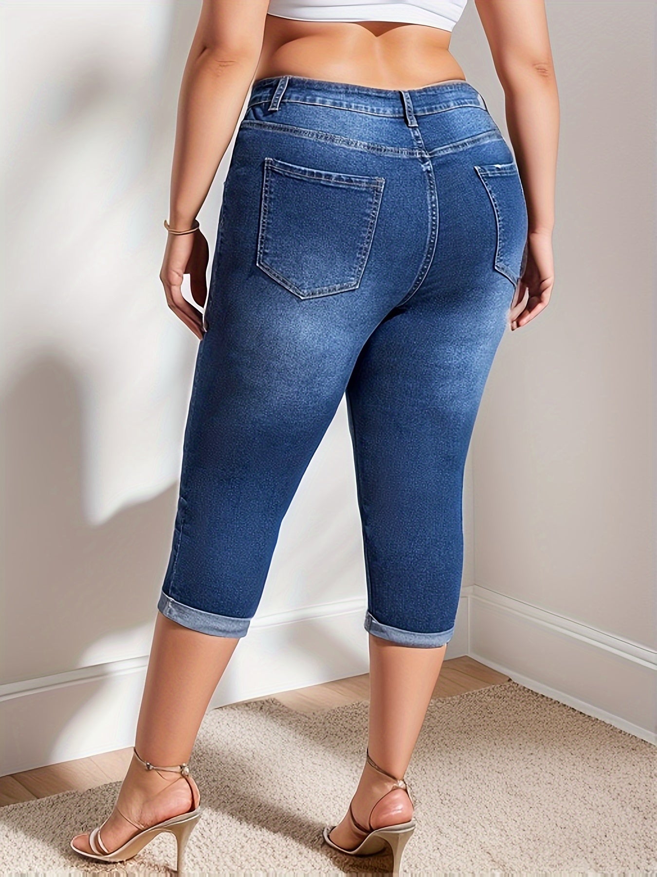 Plus size women's high stretch capri denim pants in washed blue with whiskering and roll-up hem.