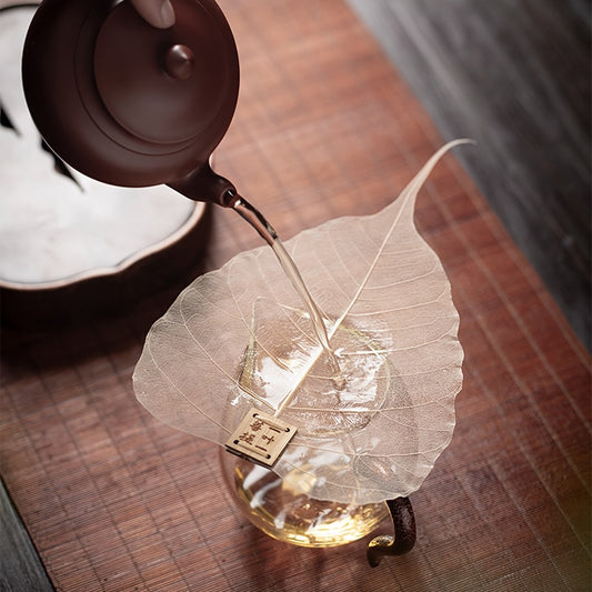 Chinese-style tea strainer shaped like a Bodhi tree leaf, made from natural wheat straw. Versatile anti-scalding tea filter with a unique bookmark design.