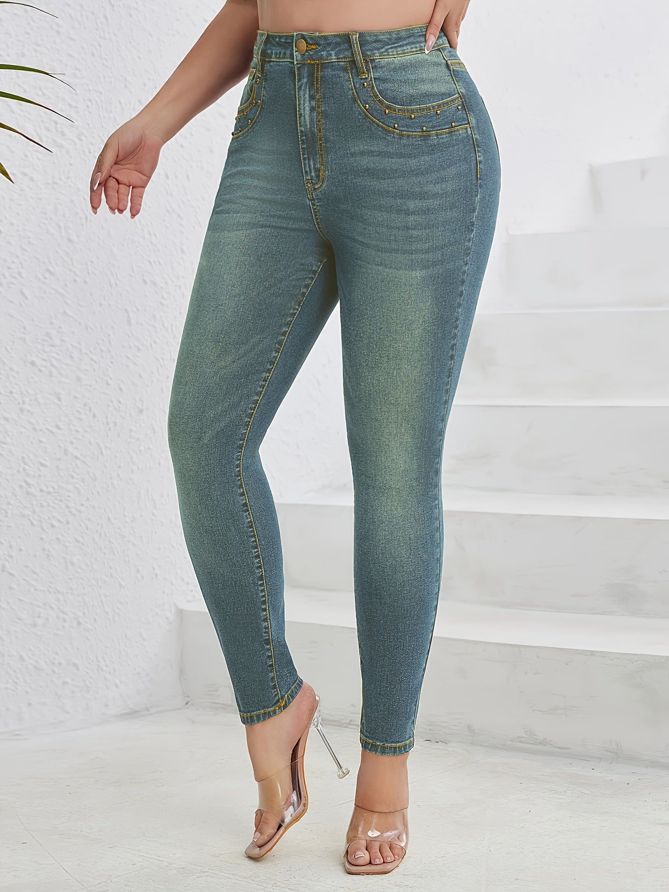 Blue studded skinny jeans for plus size women, high-waisted, casual style with embellished details. Versatile and comfortable for fall and winter.