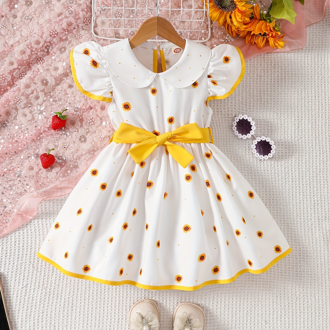 Girls' sleeveless dress with doll collar, ruffled hem, and strawberry design.