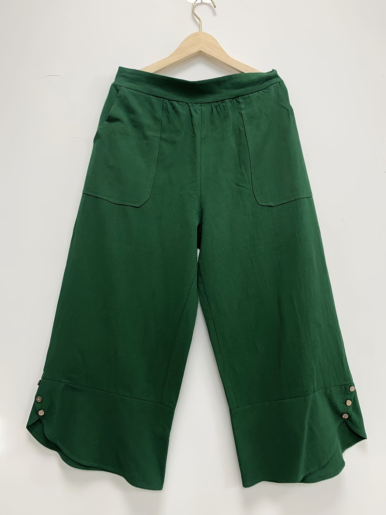 Stylish high-waisted plus-size cotton trousers with pockets, button details, solid color, and wide legs.