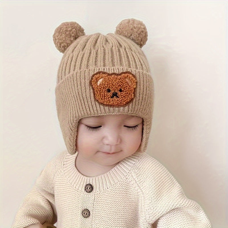 Soft polyester knit hat with cozy bear theme and ear warmers for young children, perfect winter gift for boys and girls aged 0-3 years. Comes in khaki, coffee, and ivory colors.