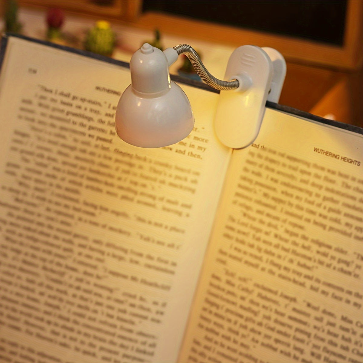 Mini portable LED book light with adjustable arm, warm light for night reading.