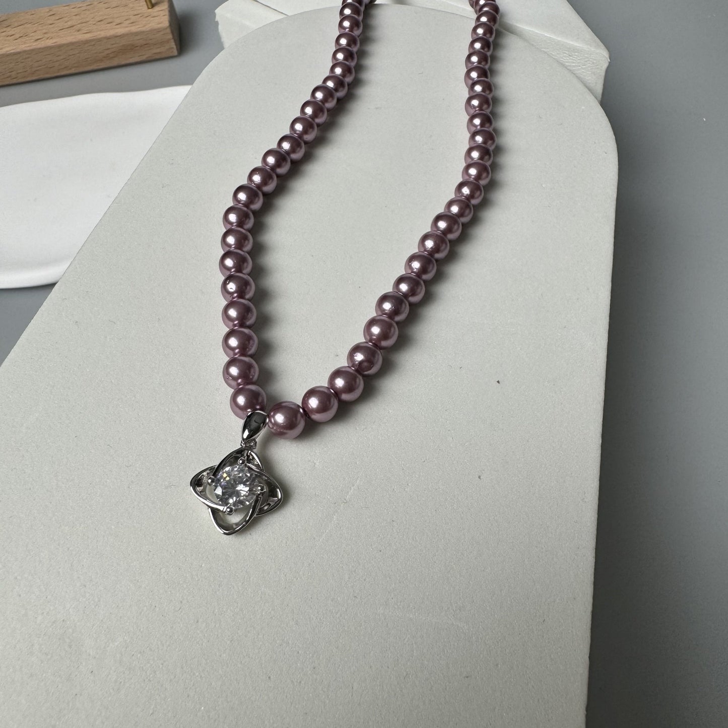 A stunning and opulent purple shell pearl necklace featuring a S925 silver clover pendant accented with inlaid zirconia. This exquisite piece is 18K golden plated and showcases the July birthstone, making it the perfect gift for your wife, daughter