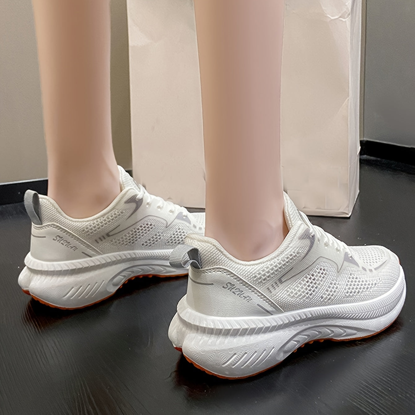 Women's low-top running shoes in white with orange sole, breathable fabric upper, rubber sole, stabilizing support, all-season casual sneakers.