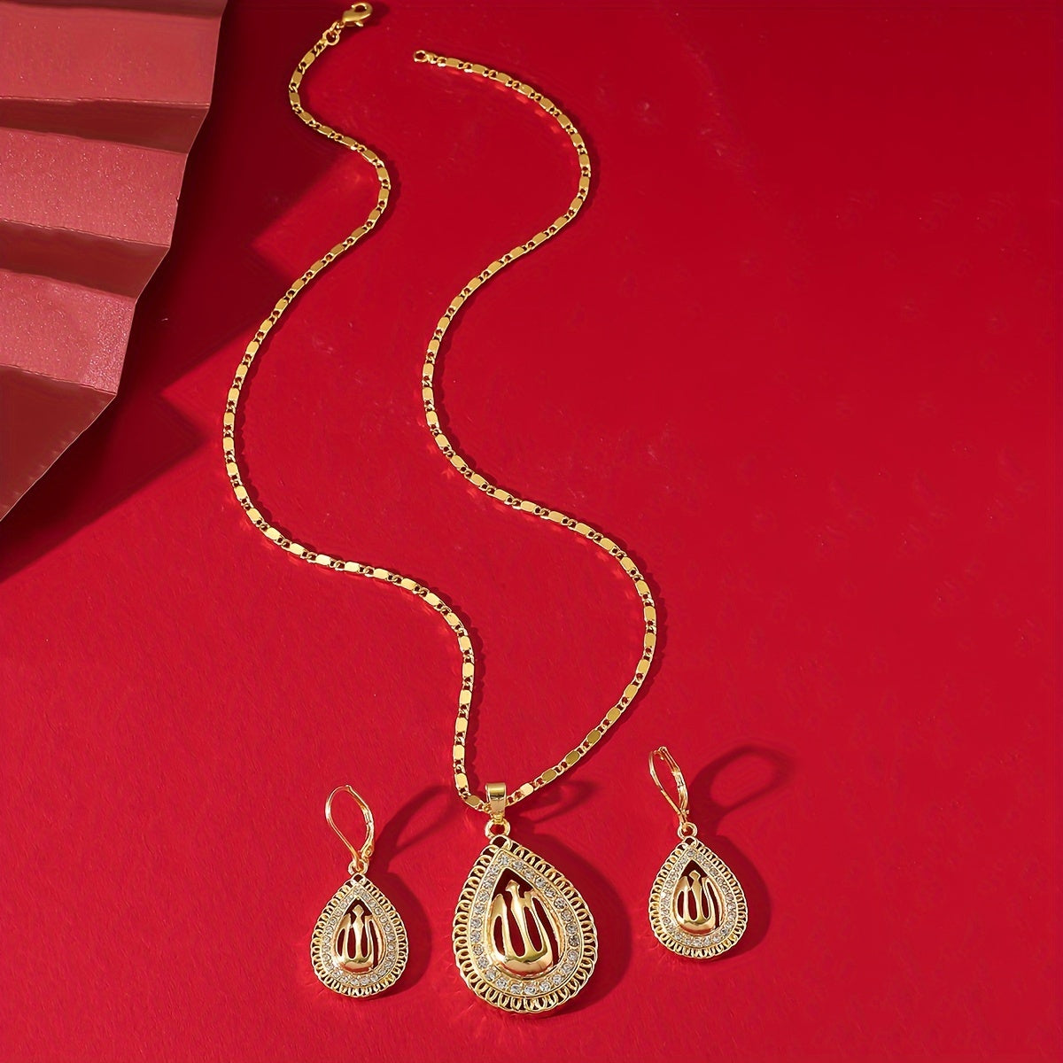 A jewelry set featuring a pendant necklace and earrings in Middle Eastern luxury style, with a golden water drop shape and interlaced lines design featuring a hollow Allah pattern.