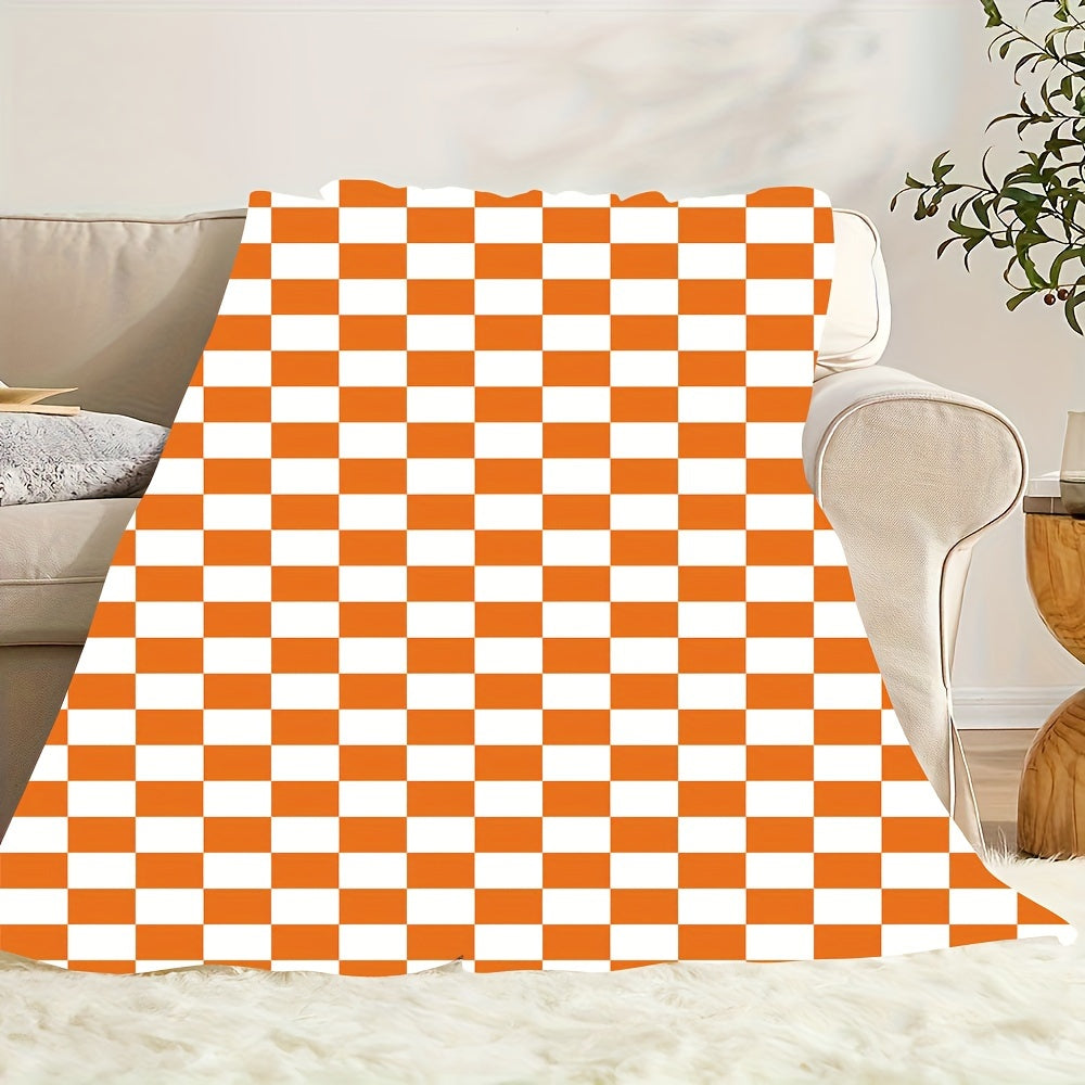 One piece of an orange and white checkered print fleece throw blanket featuring a geometric pattern. This all-season blanket is machine washable, durable, and anti-tear, making it perfect for use in the bedroom, living room, or while camping. It weighs