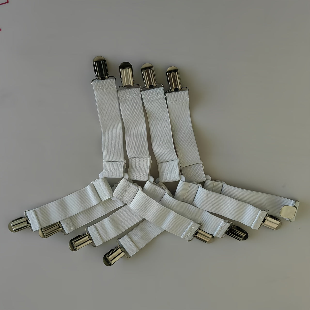 Keep your bedding in place with these 4pcs Adjustable Bed Sheet Straps. Made with non-slip nylon elastic quilt holders and invisible sofa cushion fasteners, these straps feature metal clips and non-woven fabric weaving for easy cleaning.