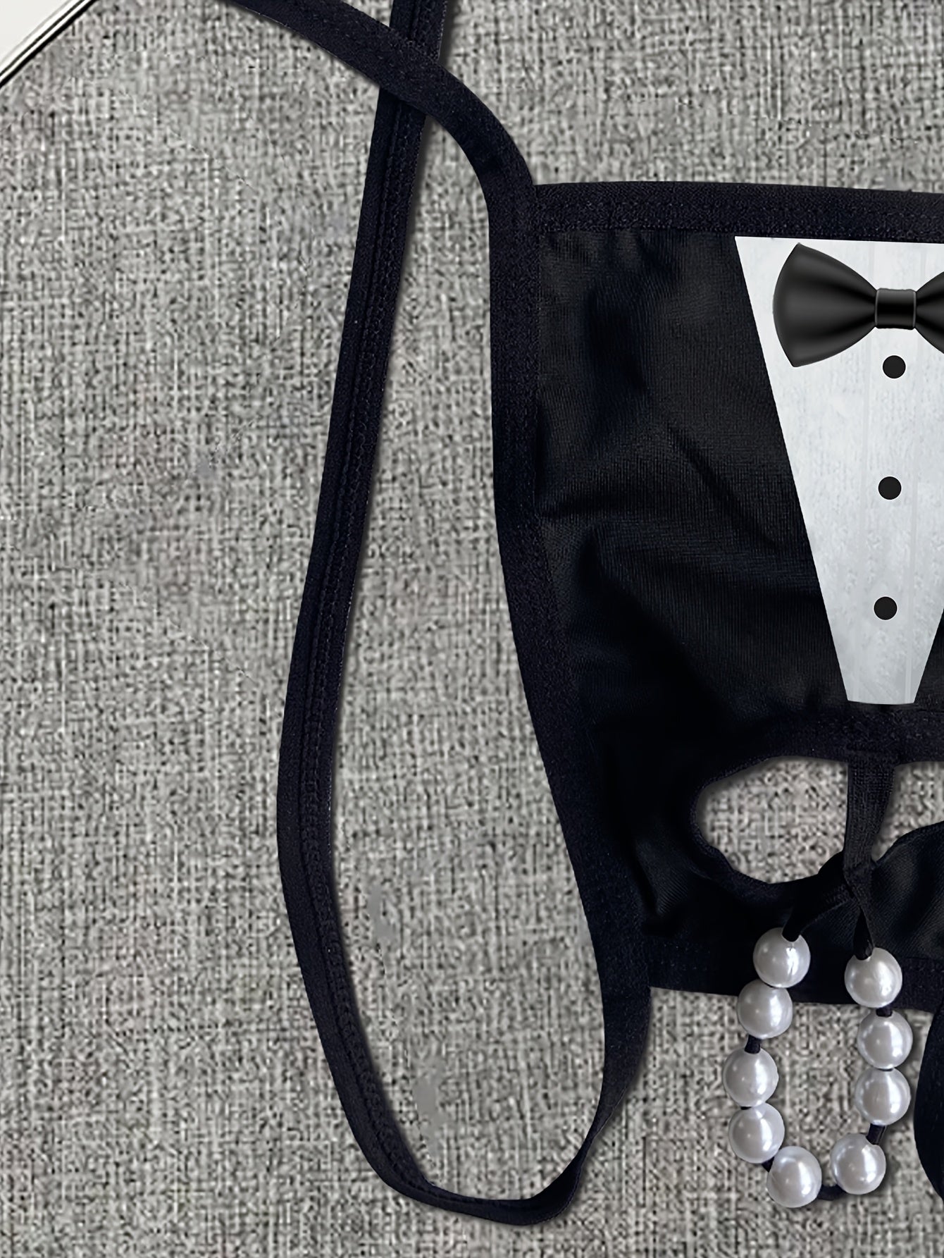 Men's novelty tuxedo print thong with beaded chain detail. Sexy lingerie in medium stretch knit fabric for a skinny fit. Ideal as a costume accessory.