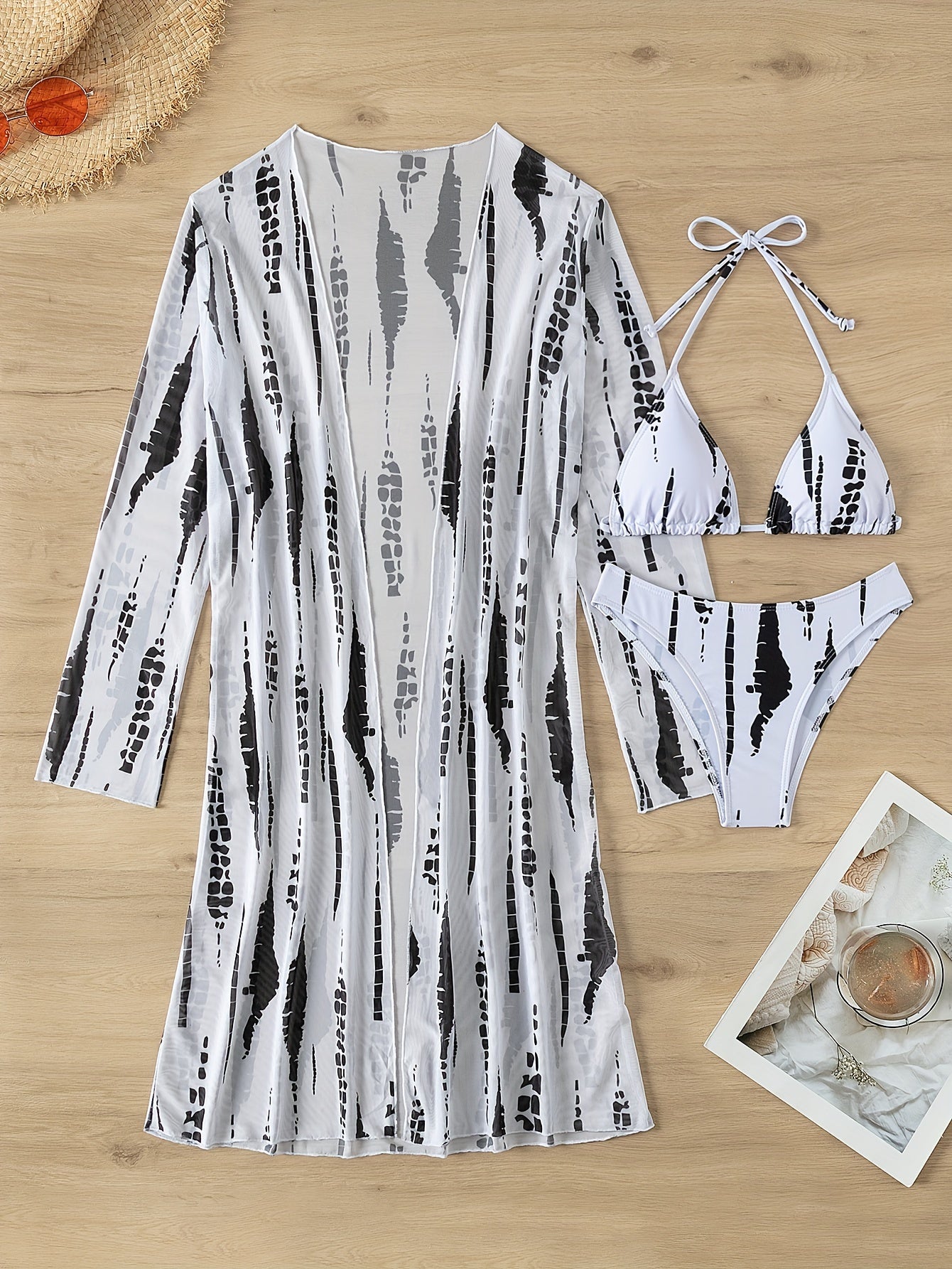 Women's strapless bikini set with long sleeve cover-up made of high stretch polyester and elastane. Features a random print, cross strap detail, swimwear with shorts bottom. No belt