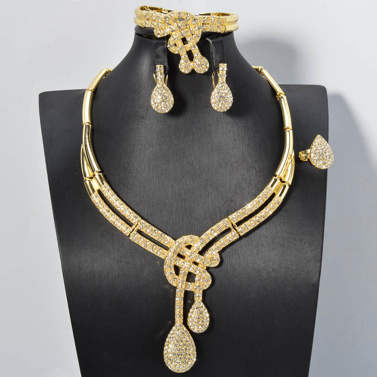 Vintage jewelry set featuring elegant geometric and musical note designs with tassel accents. Made with synthetic cubic zirconia and copper materials. Set includes a necklace, bracelet, earrings, and ring. Perfect for adding a touch of luxury sparkle to