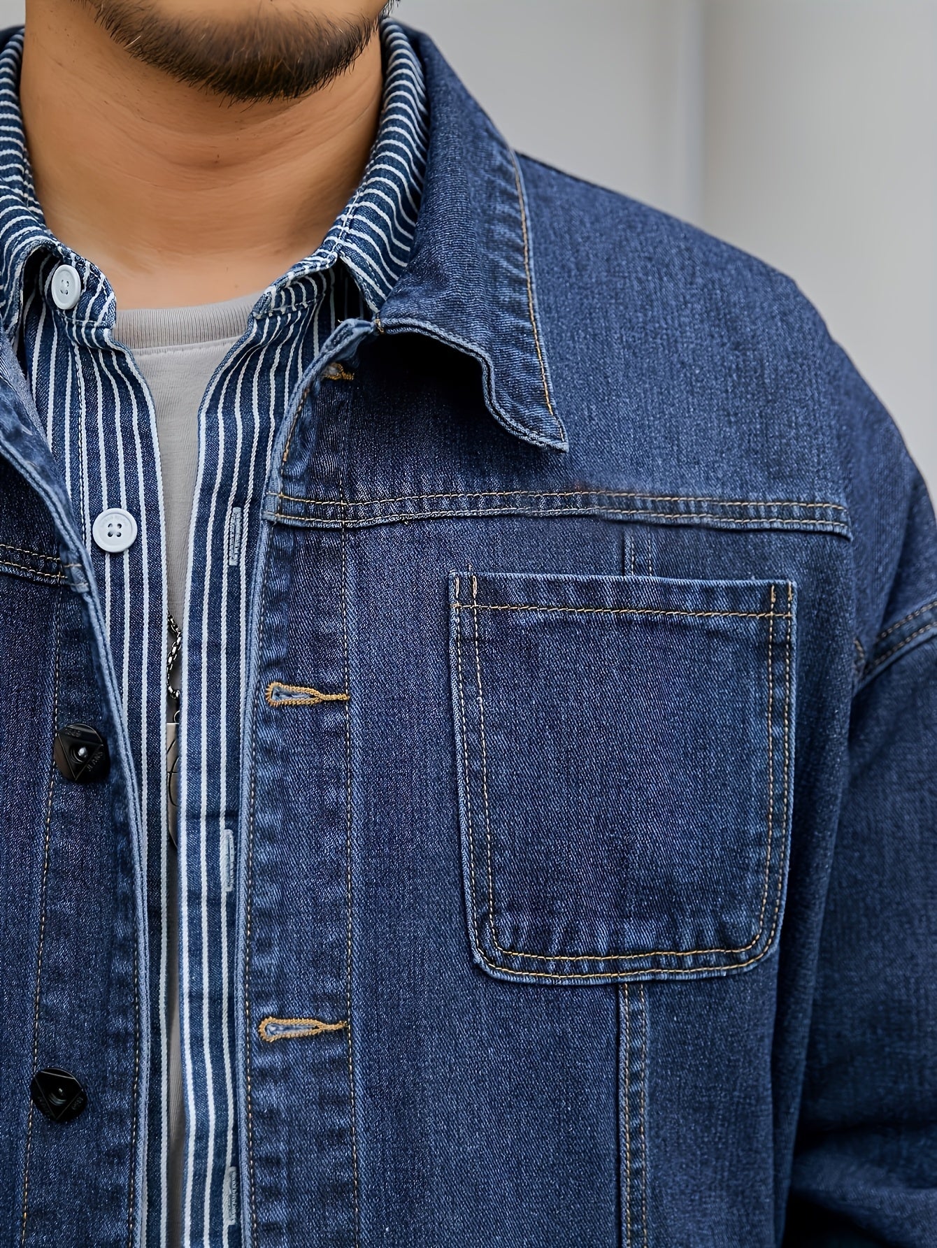 Men's plus size denim jacket in solid washed blue with long sleeves, chest pockets, button-front closure, and loose fit. Machine washable for everyday casual streetwear style with trendy