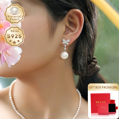 These women's fashionable dangling earrings feature a pair of 12-13mm large grains of strong light, slightly flawed round natural freshwater pearls set in S925 silver. Each earring is adorned with a delicate bow and comes in a gift box. Please note that