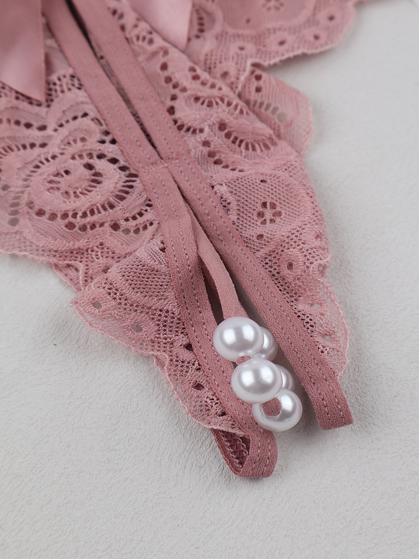 Adult drop waist thong panties with lace, bowknot, and pearls. Comfortable low-rise fit, made of a polyamide and elastane blend knit fabric in a solid color with a mature style.