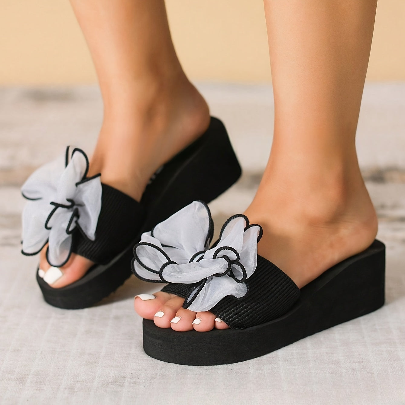 Stylish black wedge flip-flops with floral bow, slip-on design, durable non-slip EVA material, comfortable fabric upper. Perfect for summer beach outings.