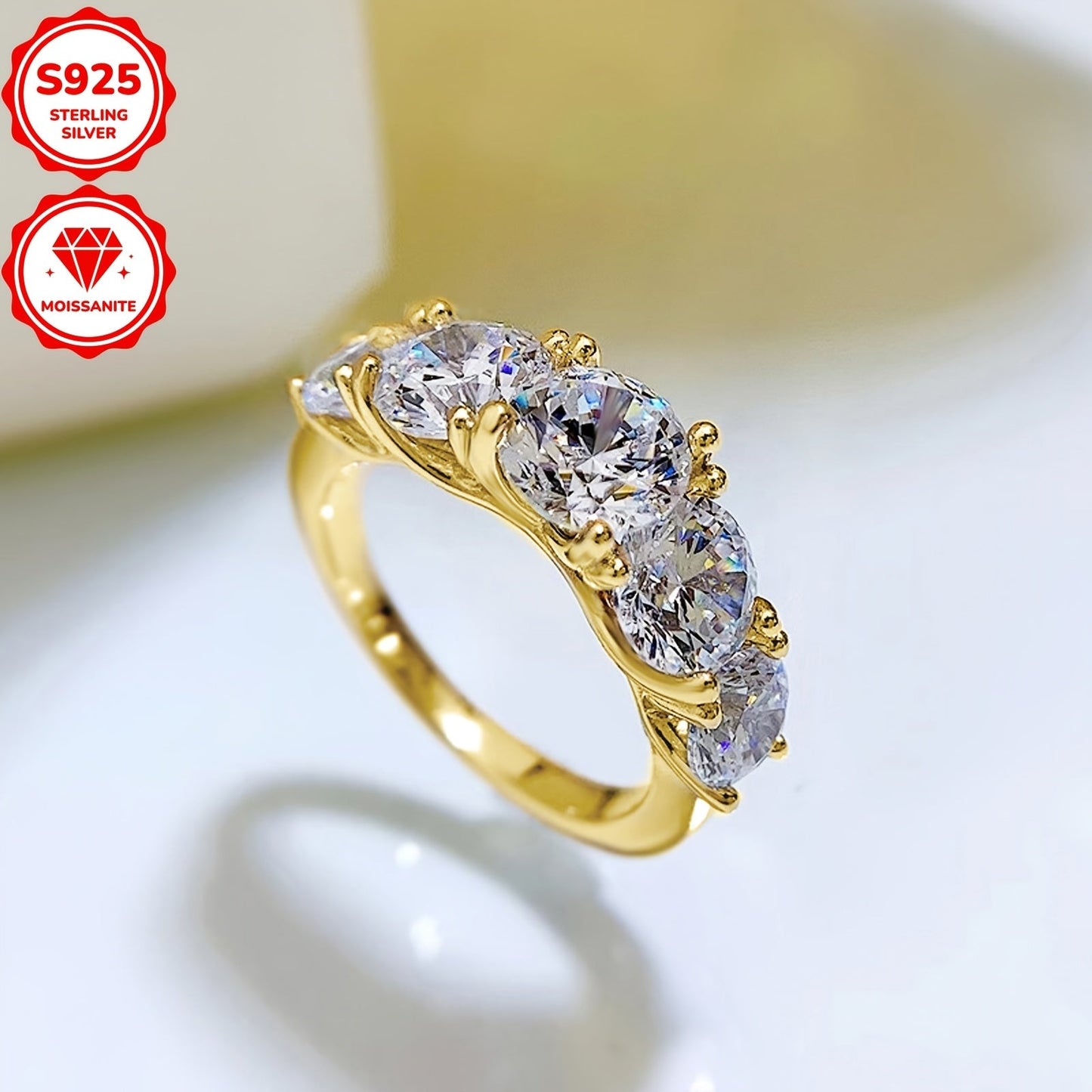 Ushbu ayollar uchun uzuk 925 sterling kumushdan tayyorlangan bo'lib, go'zal moissanite toshlari bilan bezatilgan. Uzukda 6.5mm markaziy tosh, ikkita 6mm tosh va ikkita 5mm tosh mavjud bo'lib, jami 3.60ct. Har bir tosh ehtiyotkorlik bilan o'rnatilgan.