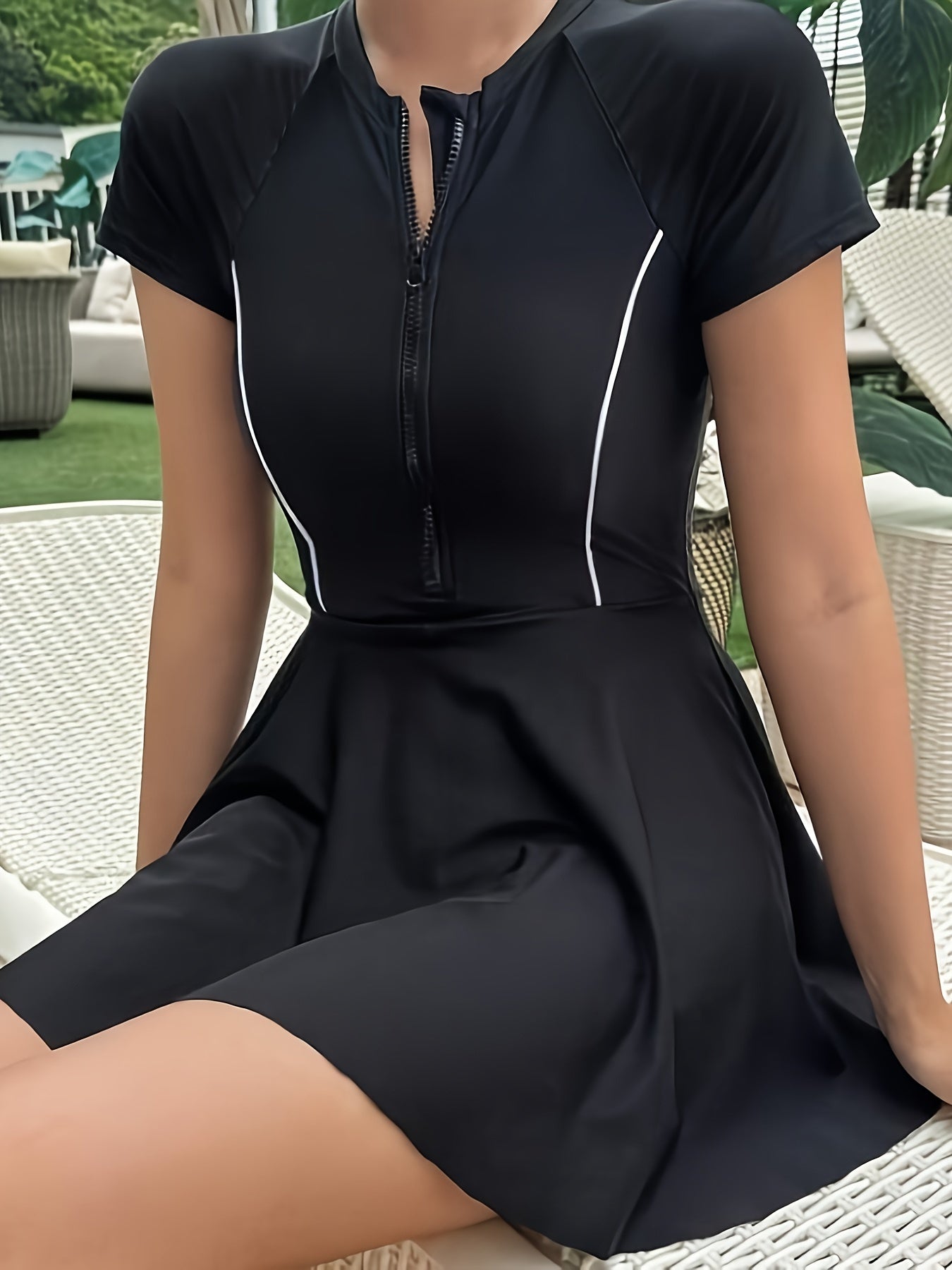 Sporty black one-piece swimsuit for women with zipper detail, made from high stretch nylon/elastane blend. Features short sleeves, round neck, and non-transparent fabric suitable for