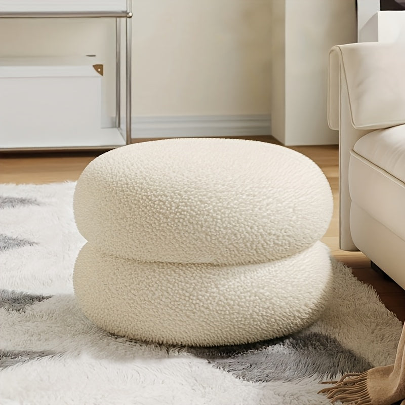 White polyester sofa stool that is versatile and compact. This round ottoman is ideal for the living room, great for changing shoes and enhancing home decor. Features a contemporary style.