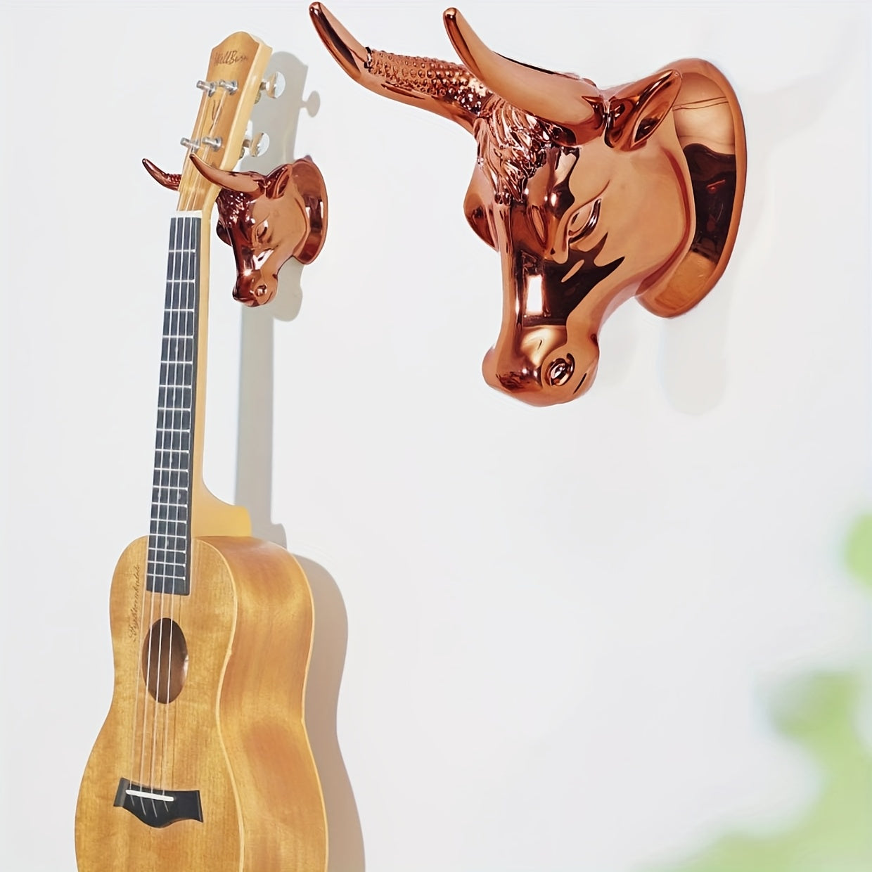 Fashionable wall mount guitar hanger in golden metal with powder coating, non-slip grip, and hook for jacket, towel, and key. Perfect for bathroom or home decoration.