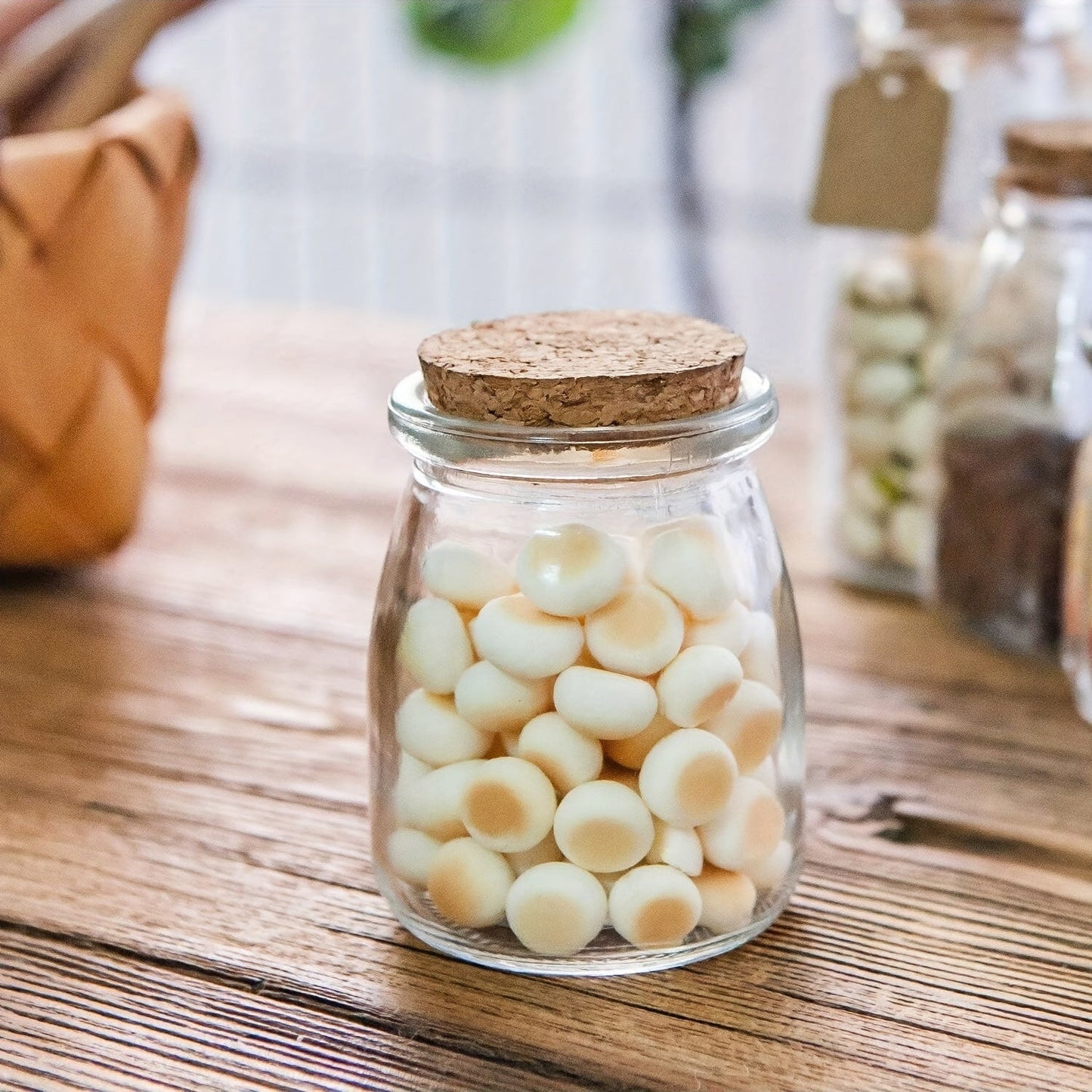 Set of 20 to 30 small glass jars with cork lids, 100ml capacity, perfect for storing yogurt, pudding, honey, and as wedding favors. Includes labels and twine for easy organization. Reusable and round containers.