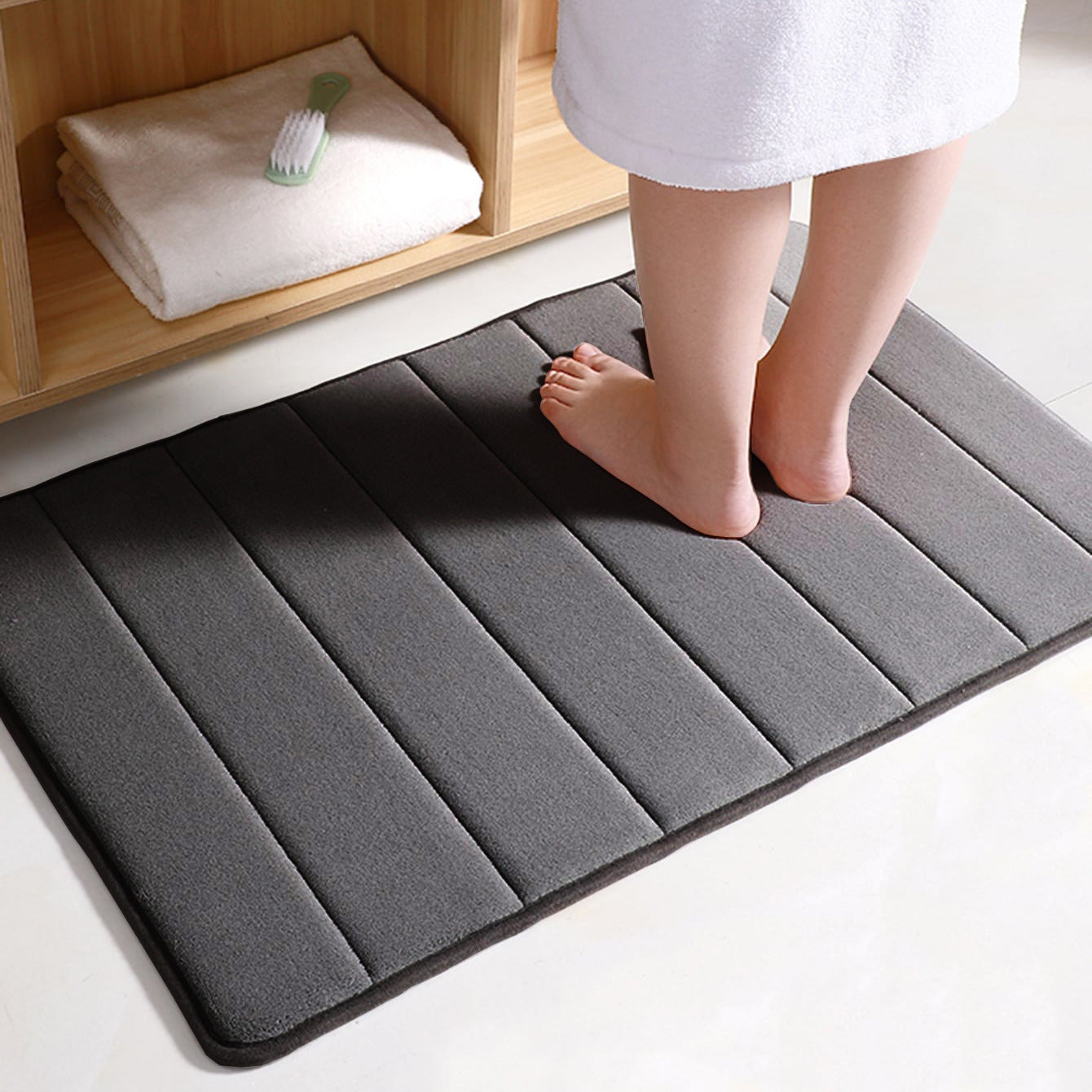 Soft polyester blend bath mat in plush dark gray stripes, featuring a non-slip PVC backing for added safety. Easily machine washable for convenience, this rectangular mat is perfect for adding comfort to your bathroom décor.