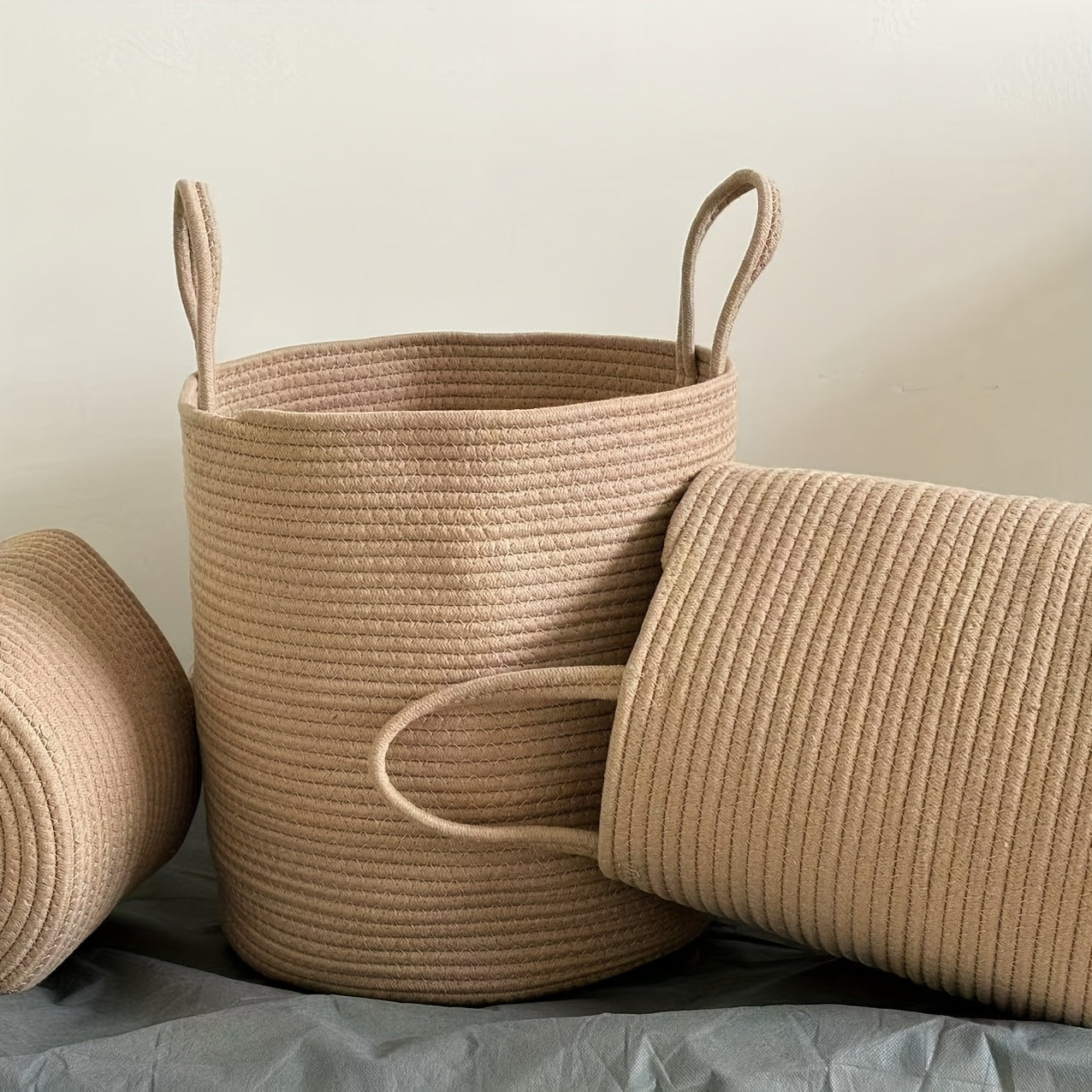 Large capacity rustic cotton rope woven laundry basket with a modern style, perfect for organizing clothes in your home. This round-shaped basket has handles for easy transportation and is ideal for use in the laundry room. No lining included.