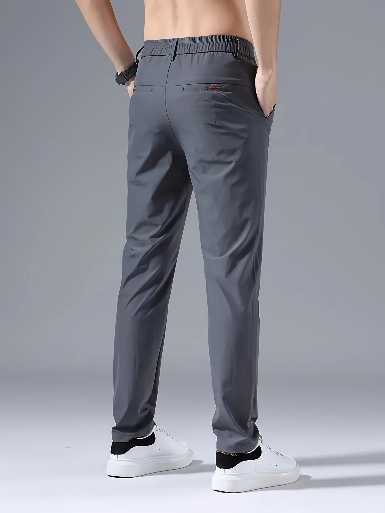 Men's slim fit casual pants made of breathable nylon fabric with pockets and embroidery. Suitable for outdoor and daily wear in a solid color basic style. Features zippered waist for