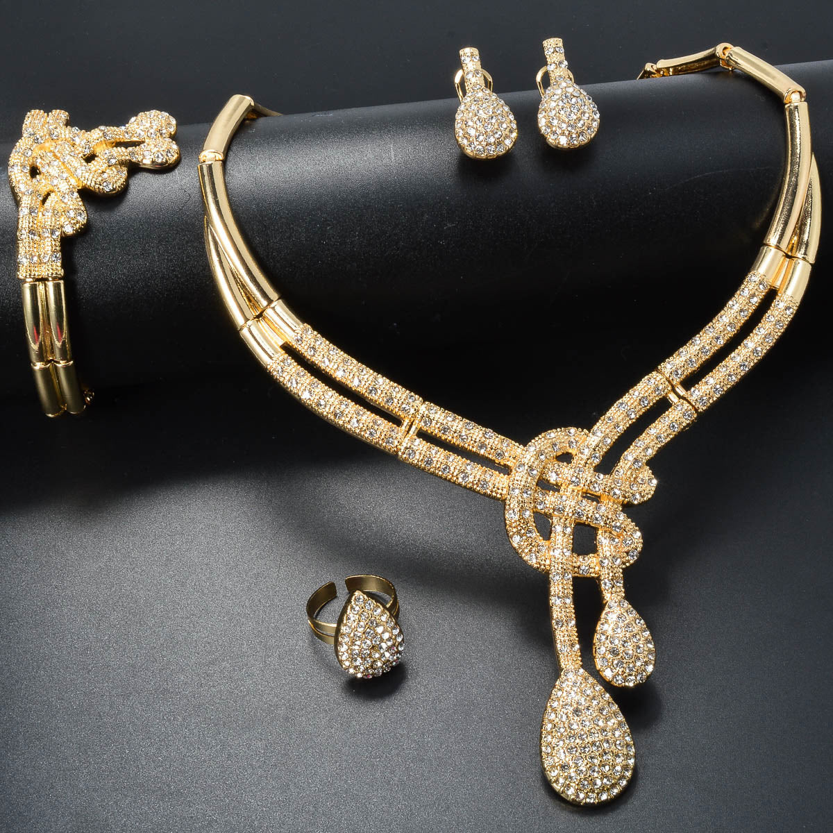 Vintage jewelry set featuring elegant geometric and musical note designs with tassel accents. Made with synthetic cubic zirconia and copper materials. Set includes a necklace, bracelet, earrings, and ring. Perfect for adding a touch of luxury sparkle to