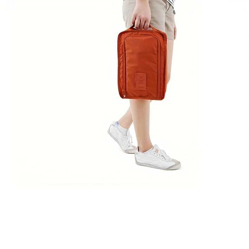 Orange shoe storage bag with mesh front pocket, zippered closure, lightweight material for neat shoe organization.