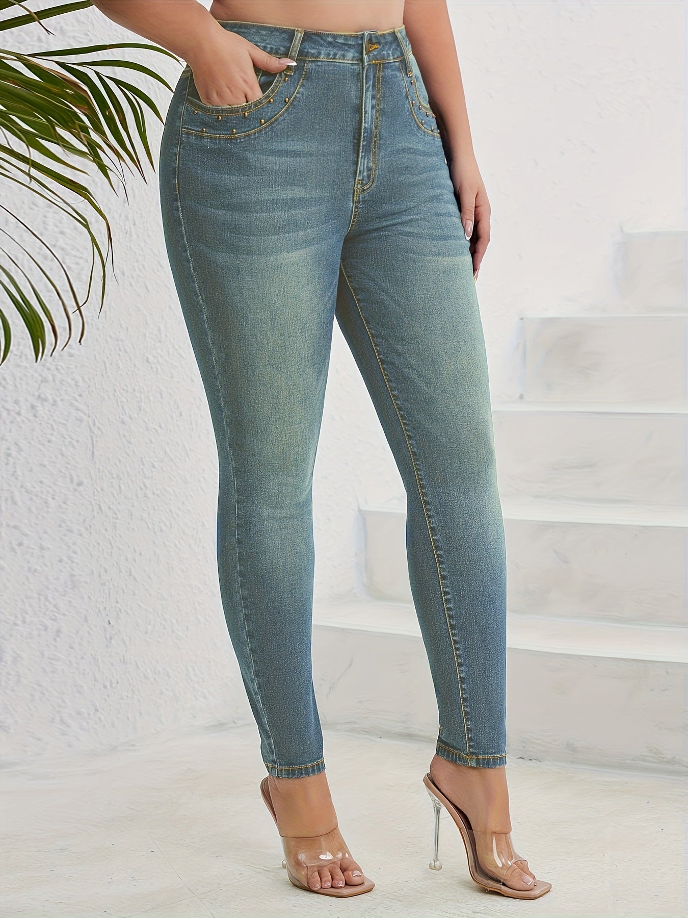 Blue studded skinny jeans for plus size women, high-waisted, casual style with embellished details. Versatile and comfortable for fall and winter.