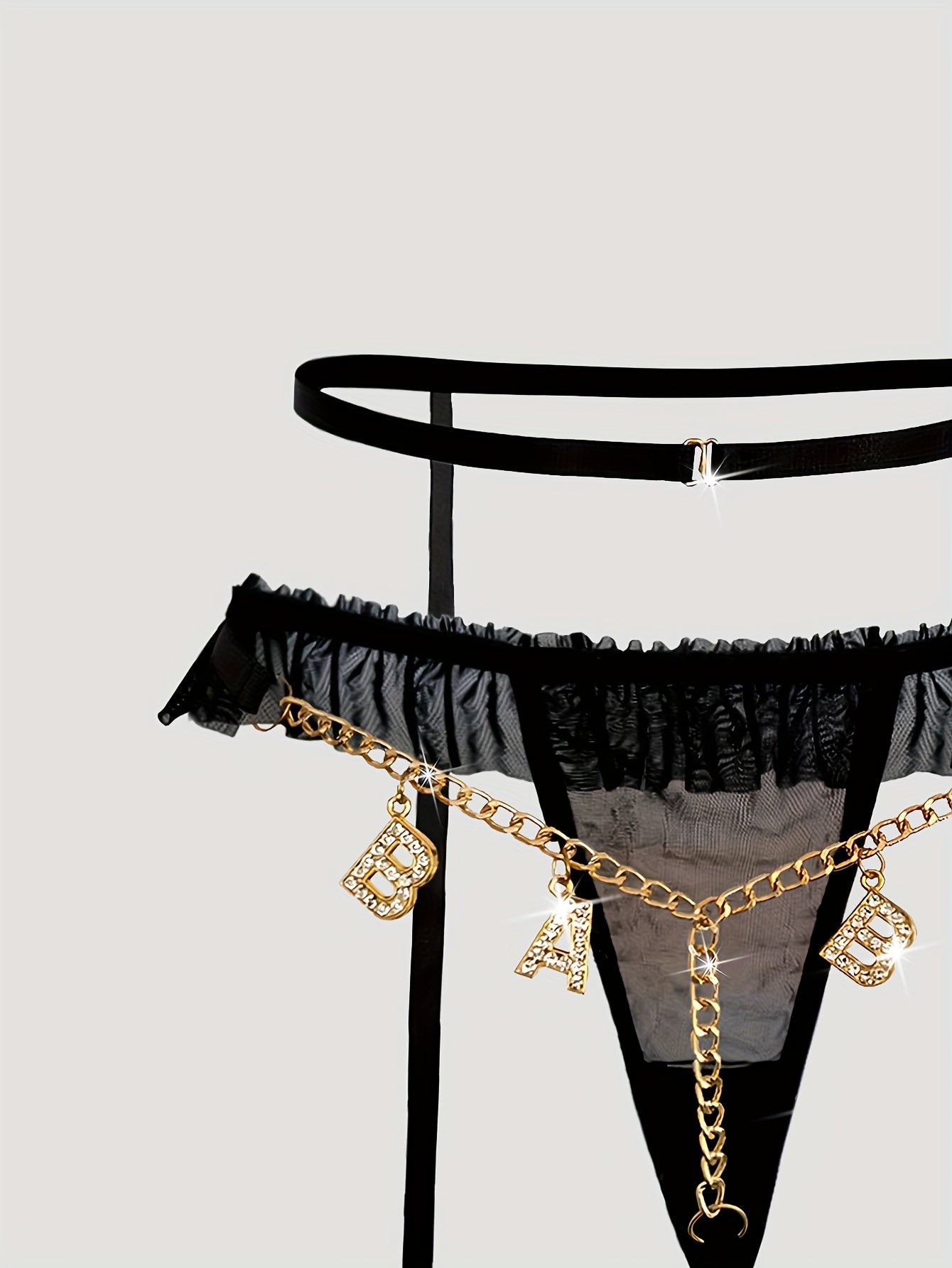 Seductive mesh garter set with gold chain, bow, and letter T-back.