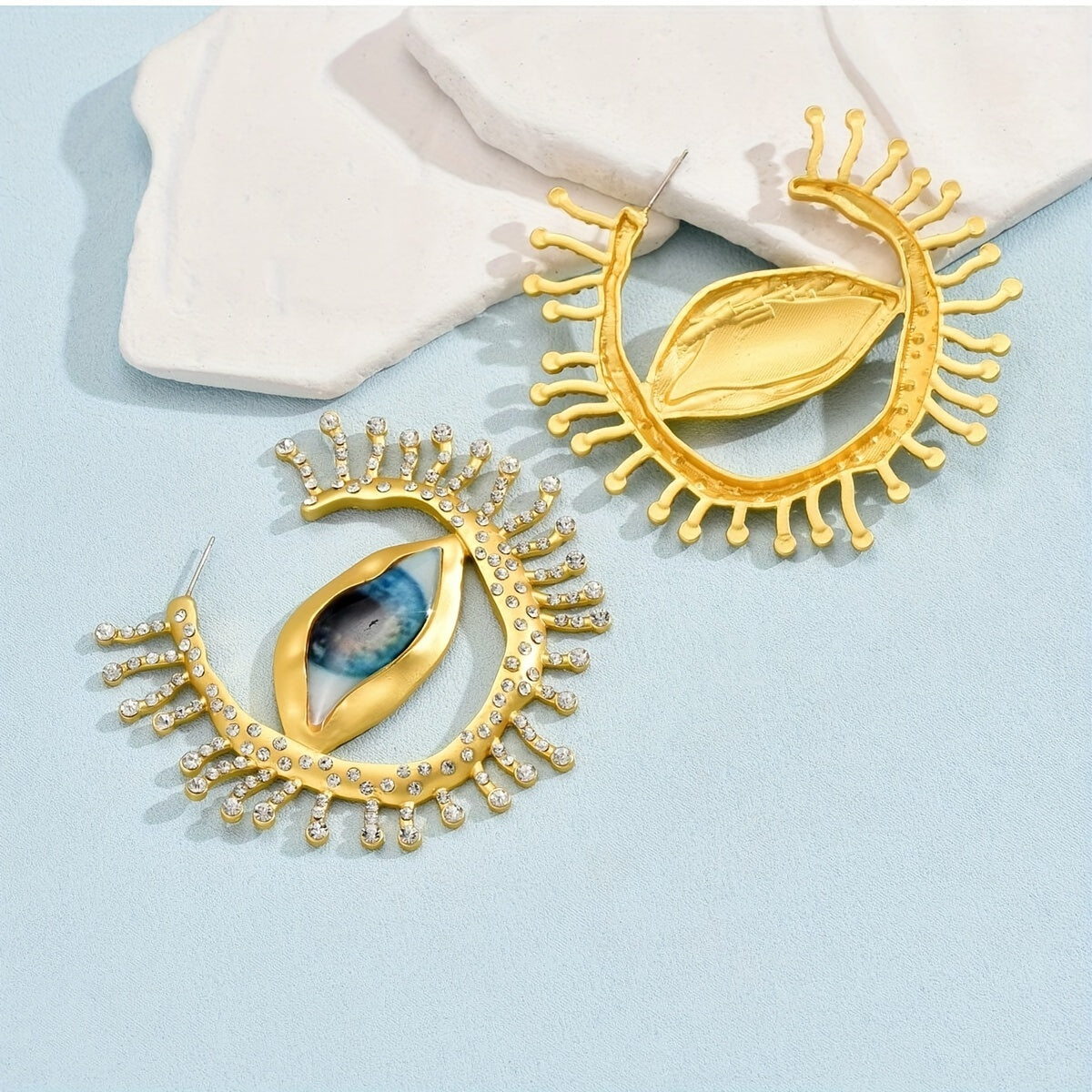 These punk cool style statement earrings feature an exaggerated eye-shaped design with metallic rhinestones. Perfect for parties, vacations, and everyday wear. Add a unique touch to your jewelry collection with this bold pair of dangle earrings.