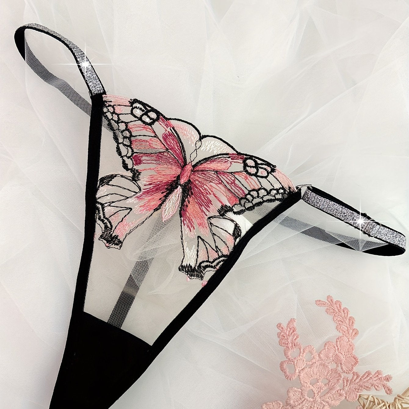 Hand-washable purple thong with butterfly embroidery and glitter trim, made of semi-sheer polyester blend.