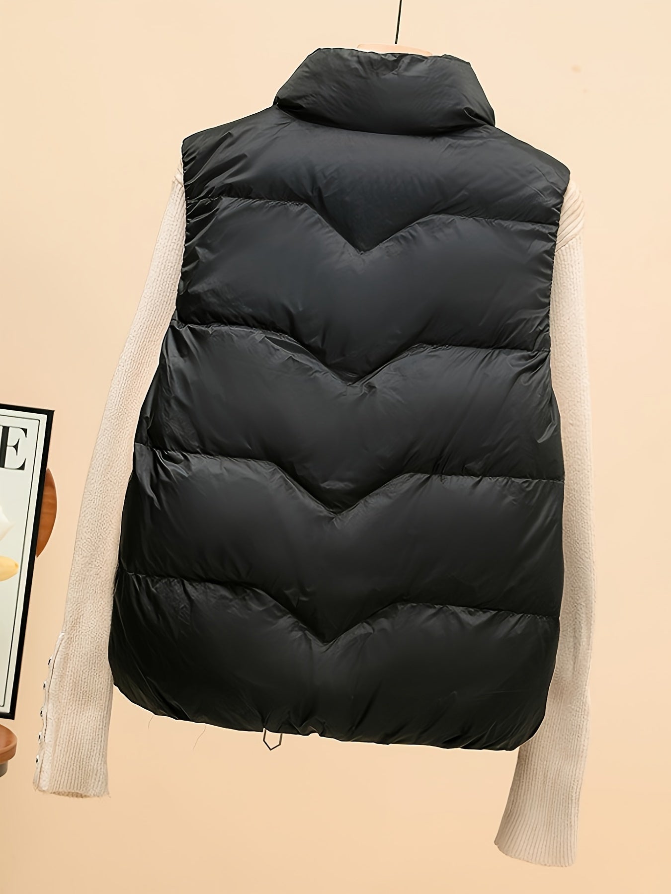 Sleeveless beige duck down vest with side pockets and zip-up closure. Perfect for fall/winter layering with a loose fit and 80g white duck down fill. Made of polyester with a glossy finish.