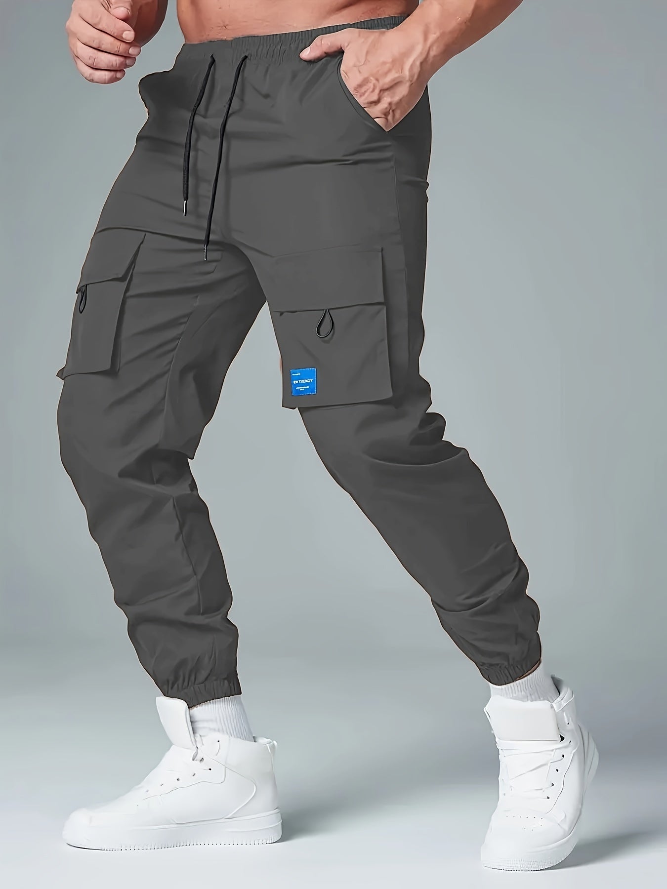 Men's casual drawstring cargo pants with multiple pockets made of polyester, mid-waist, ideal for spring and fall seasons.