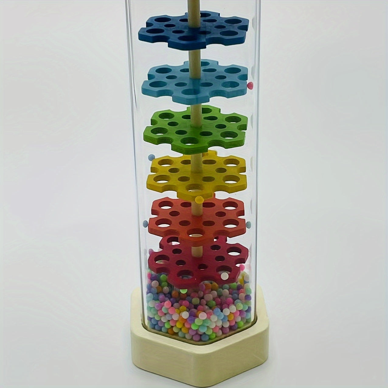 Musical instrument for babies that simulates the soothing sound of rain in a wooden tube, similar to a rainbow hourglass sandbell.